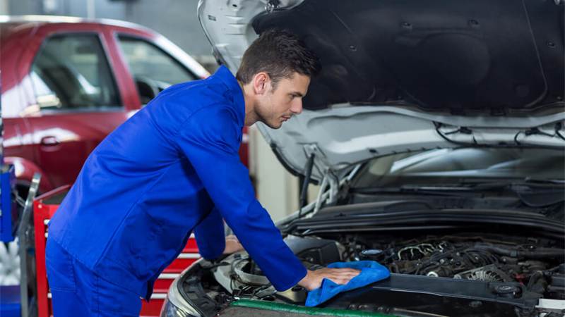 Mechanic inspecting a vehicle engine under the hood